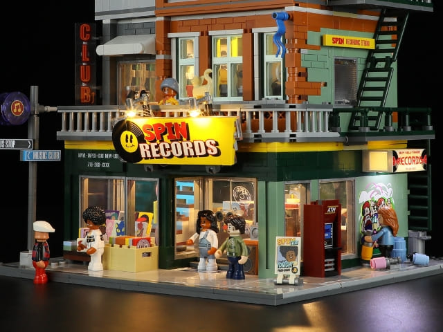 Funwhole Spin Records Klemmbaustein-Set F9058: Beleuchteter Plattenladen bei Nacht mit aktiven LED-Lichtern und Minifiguren auf der Straße.